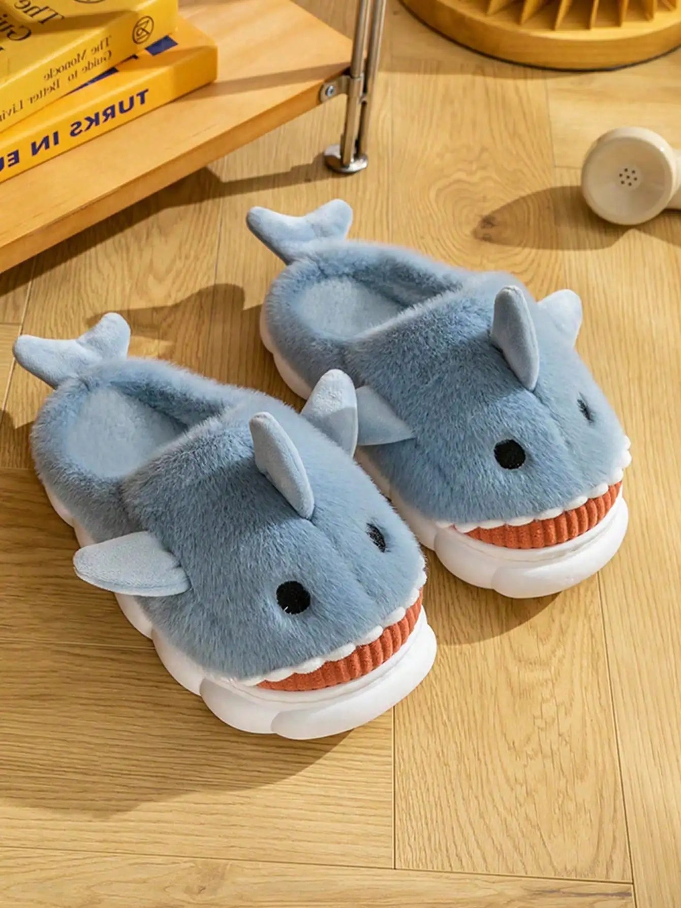 Plush blue shark slippers on wood floor